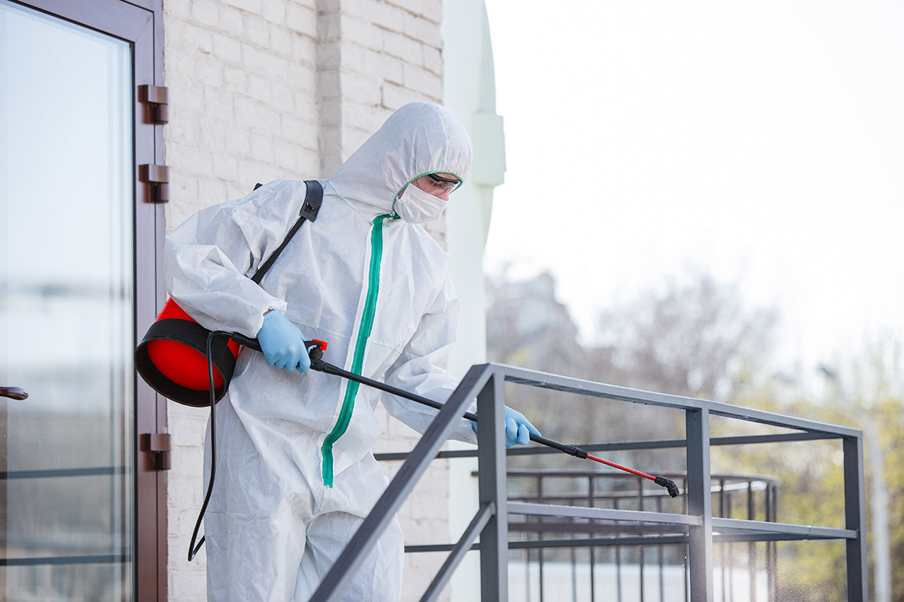 Coronavirus Pandemic. A disinfector in a protective suit and mask sprays disinfectants in the room. Protection of COVID-19 disease. Prevention of spreding pneumonia virus with surfaces we touch.